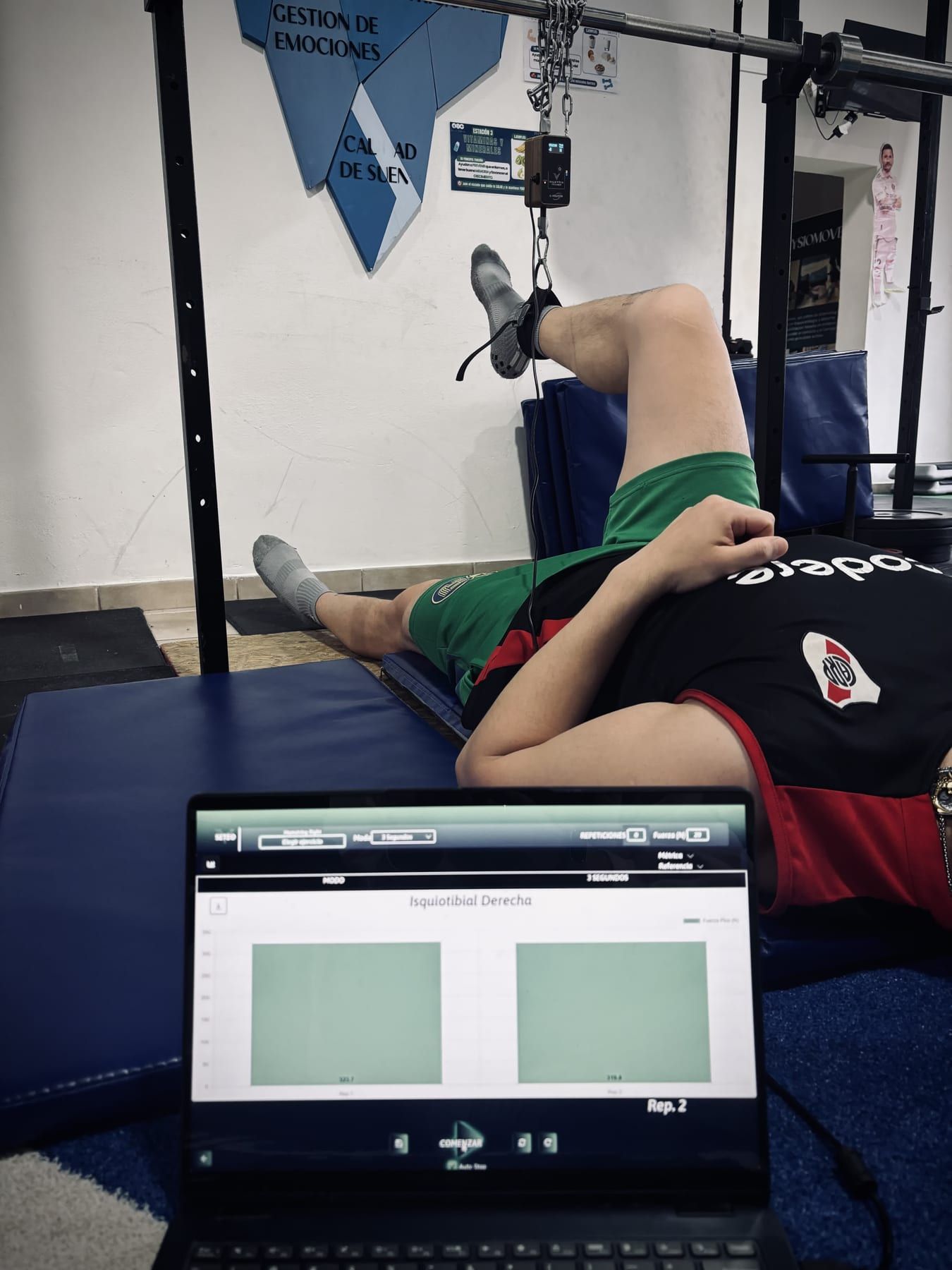 Test de fuerza con dinamómetro IVOLUTION en PhysioMove: el deportista en la colchoneta con la cinta en la pierna y la curva del test en la laptop