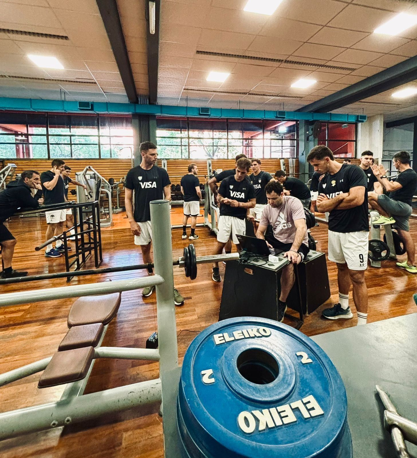 Plantel de rugby alrededor de la estación de registro durante una evaluación de fuerza en el gimnasio