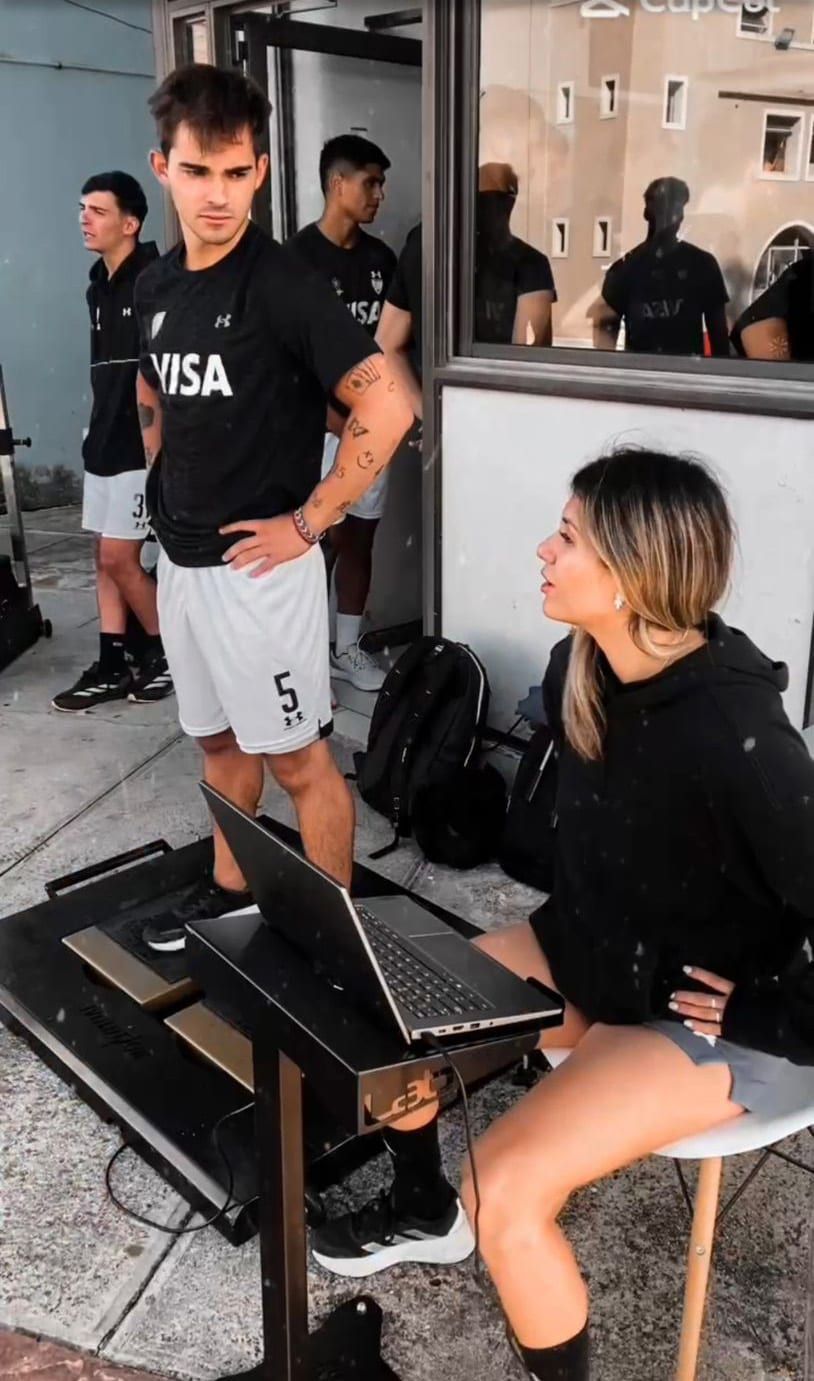 Jugador de rugby sobre la plataforma de salto durante una evaluación, con una kinesióloga revisando los datos en la laptop