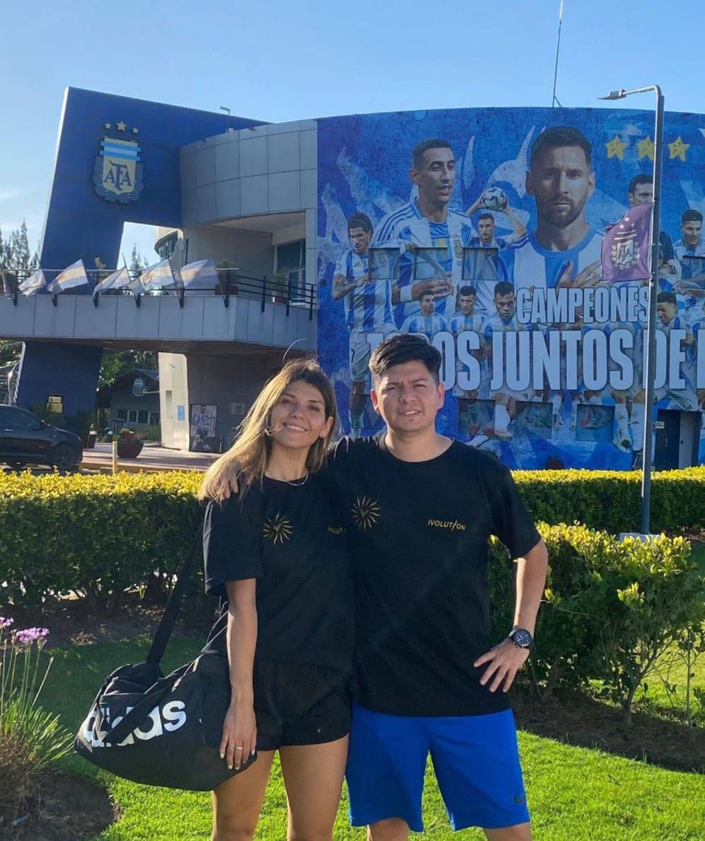 Dos integrantes del equipo frente al mural de los campeones en el Predio de AFA