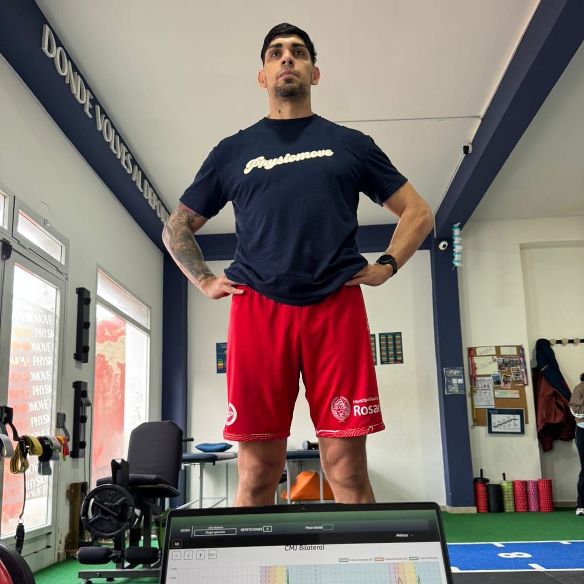 Deportista de pie sobre la plataforma de salto con la curva del test en la laptop
